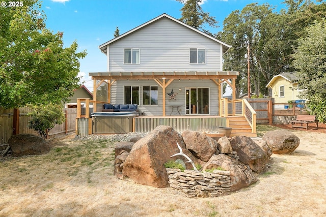 rear view of house with a wooden deck and a hot tub