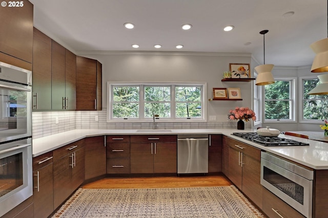 kitchen with light wood-style floors, a sink, appliances with stainless steel finishes, and light countertops