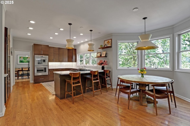 kitchen featuring decorative backsplash, stainless steel double oven, light countertops, ornamental molding, and recessed lighting