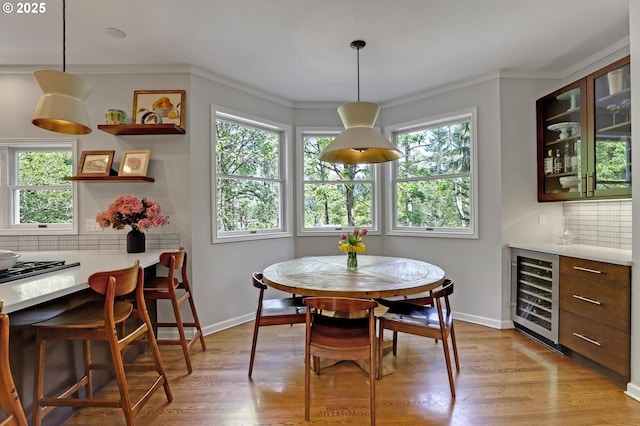 dining room with beverage cooler, plenty of natural light, light wood-style flooring, and a dry bar