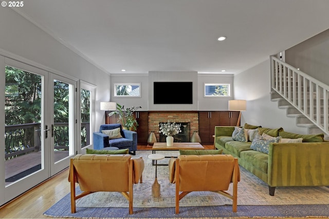 living area with crown molding, a brick fireplace, stairs, wood finished floors, and recessed lighting