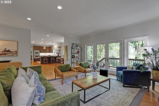 living area featuring recessed lighting, ornamental molding, and light wood-type flooring