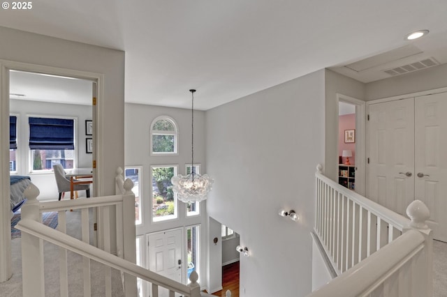stairway with visible vents and an inviting chandelier