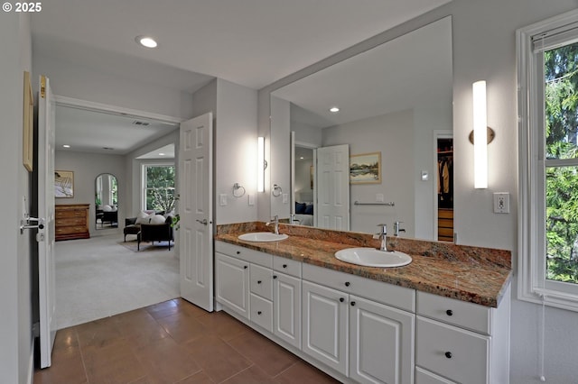 full bath with double vanity, plenty of natural light, and a sink