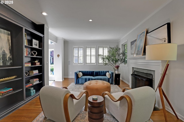 sitting room featuring recessed lighting, a glass covered fireplace, ornamental molding, and wood finished floors