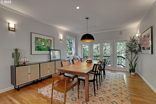 dining room with crown molding, baseboards, plenty of natural light, and light wood-style flooring
