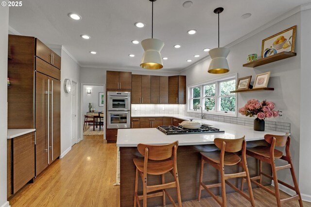 kitchen with recessed lighting, ornamental molding, a peninsula, and stainless steel appliances