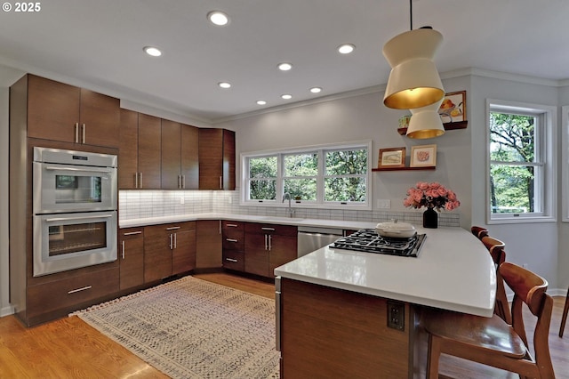 kitchen featuring ornamental molding, a peninsula, a sink, appliances with stainless steel finishes, and backsplash