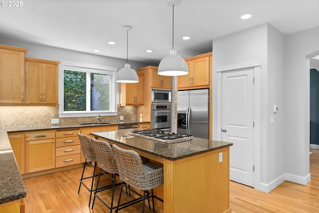 18287 SW Florendo Ln, Beaverton, OR 97007 - kitchen with appliances with stainless steel finishes, a center island, light wood-type flooring, tasteful backsplash, and recessed lighting
