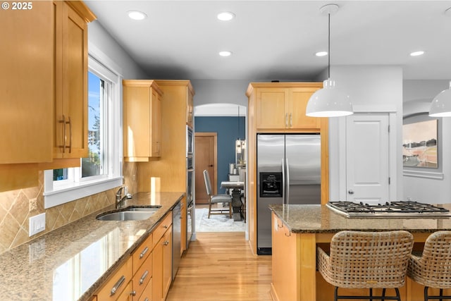 18287 SW Florendo Ln, Beaverton, OR 97007 - kitchen featuring stainless steel appliances, light wood-type flooring, a kitchen breakfast bar, pendant lighting, and dark stone counters