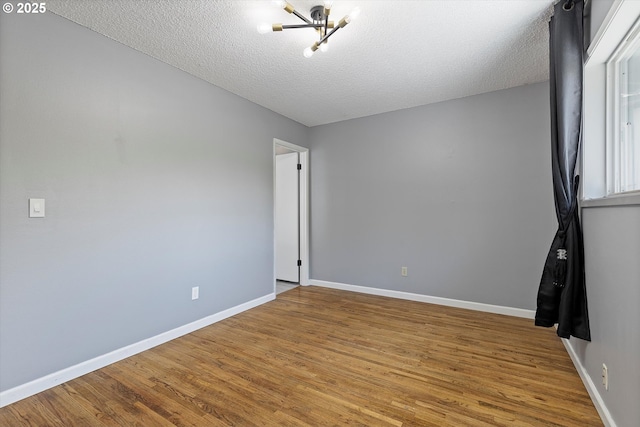 721 NW 76th St, Vancouver, WA 98665 - spare room with a chandelier, wood finished floors, baseboards, and a textured ceiling