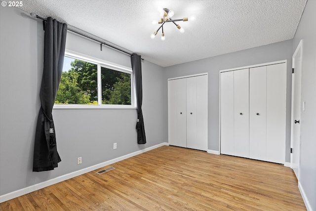 721 NW 76th St, Vancouver, WA 98665 - unfurnished bedroom featuring two closets, a textured ceiling, light wood finished floors, baseboards, and a chandelier