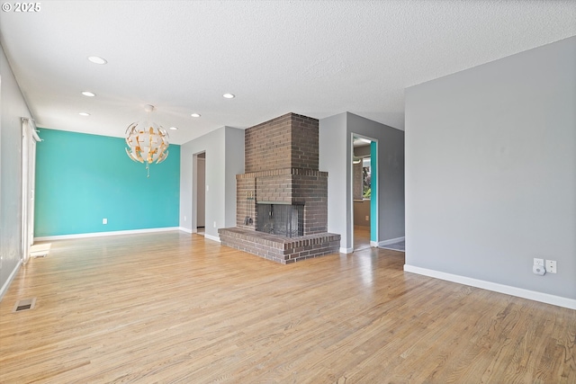 721 NW 76th St, Vancouver, WA 98665 - unfurnished living room featuring light wood-style flooring, a chandelier, baseboards, recessed lighting, and a brick fireplace