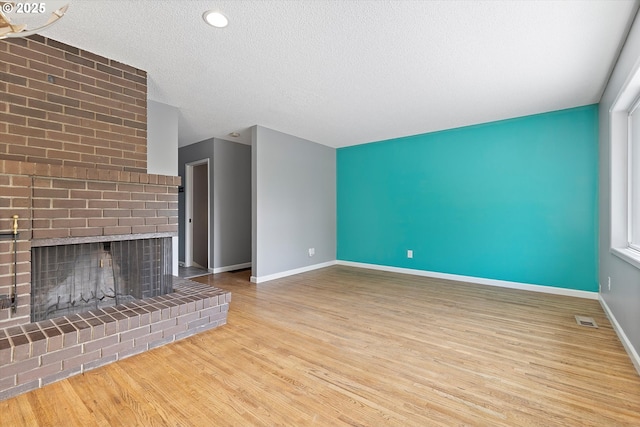 721 NW 76th St, Vancouver, WA 98665 - unfurnished living room featuring baseboards, wood finished floors, a textured ceiling, and a brick fireplace