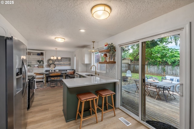 1001 S Grant St, Canby, OR 97013 - kitchen featuring open shelves, stainless steel fridge, a textured ceiling, light wood finished floors, and a peninsula