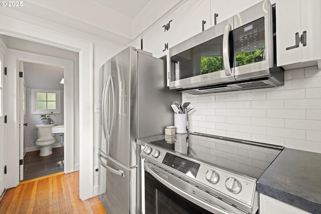 1667 Lake Front Rd, Lake Oswego, OR 97034 - kitchen with stainless steel appliances, white cabinetry, dark countertops, and light wood-style floors