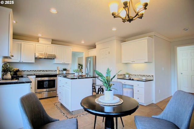 kitchen featuring under cabinet range hood, stainless steel appliances, a kitchen island, dark countertops, and crown molding