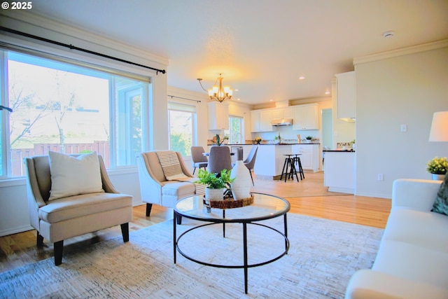 living area with baseboards, light wood-style flooring, ornamental molding, a notable chandelier, and recessed lighting