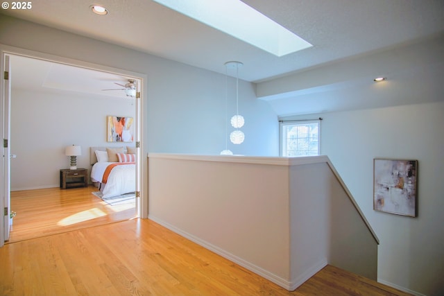 hall featuring baseboards, wood finished floors, an upstairs landing, and recessed lighting