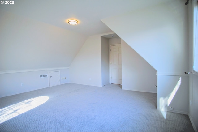 additional living space featuring carpet, visible vents, and vaulted ceiling