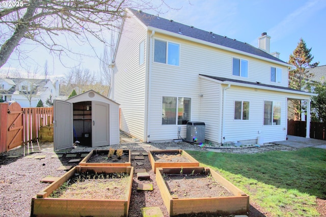 back of property featuring an outbuilding, central AC unit, a garden, a shed, and a fenced backyard