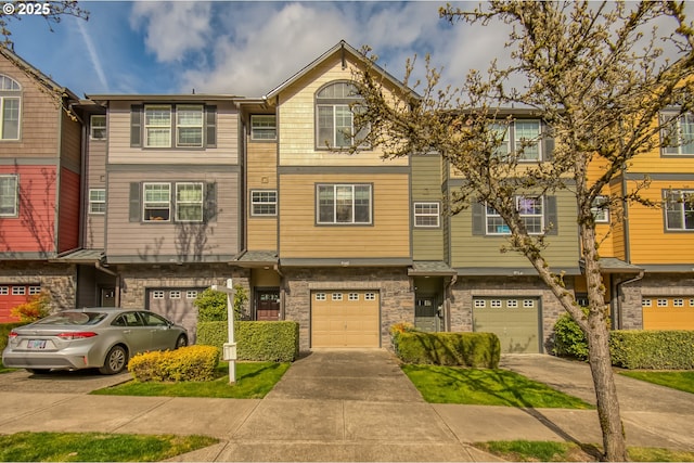 townhome / multi-family property featuring a garage, driveway, and stone siding