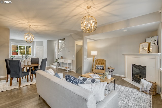 living room with wood-type flooring, a fireplace, and a notable chandelier