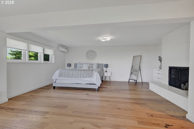 2435 Skyline Blvd, Eugene, OR 97403 - bedroom featuring a wall mounted AC, a fireplace, light wood-type flooring, and baseboards