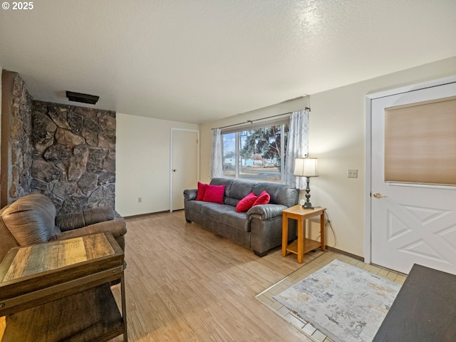 living room with baseboards, light wood-type flooring, and a textured ceiling