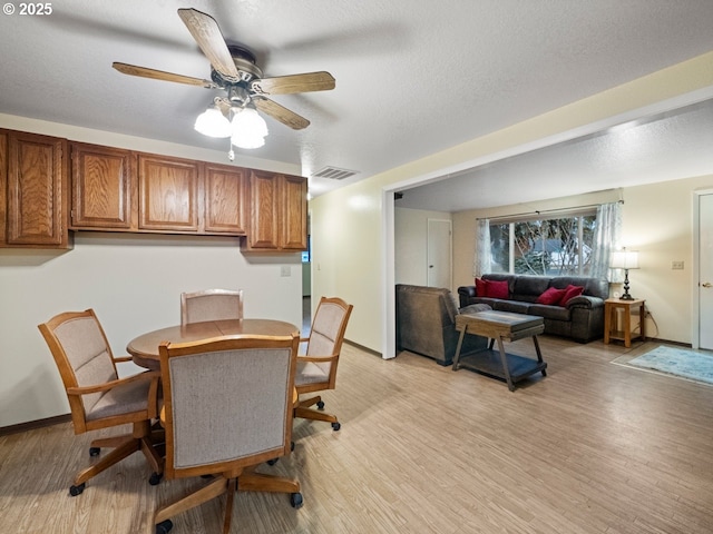 dining space featuring a textured ceiling, visible vents, light wood finished floors, and ceiling fan