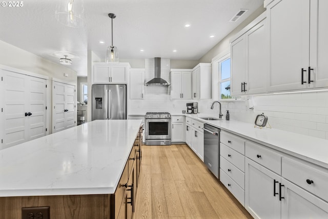 32750 Macy St, Eugene, OR 97408 - kitchen featuring appliances with stainless steel finishes, wall chimney range hood, decorative backsplash, light wood finished floors, and recessed lighting