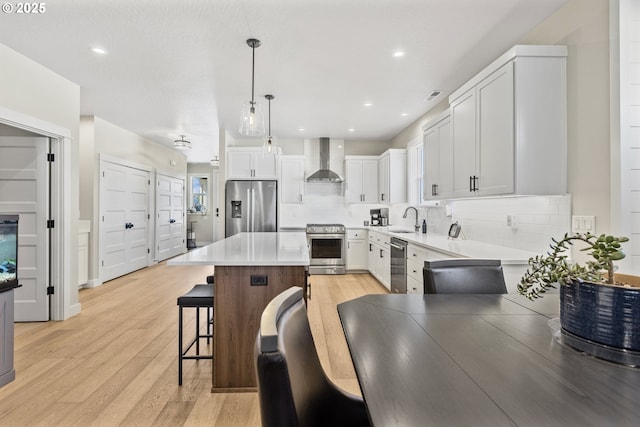 32750 Macy St, Eugene, OR 97408 - kitchen with stainless steel appliances, wall chimney exhaust hood, a breakfast bar, decorative backsplash, and light wood-style floors