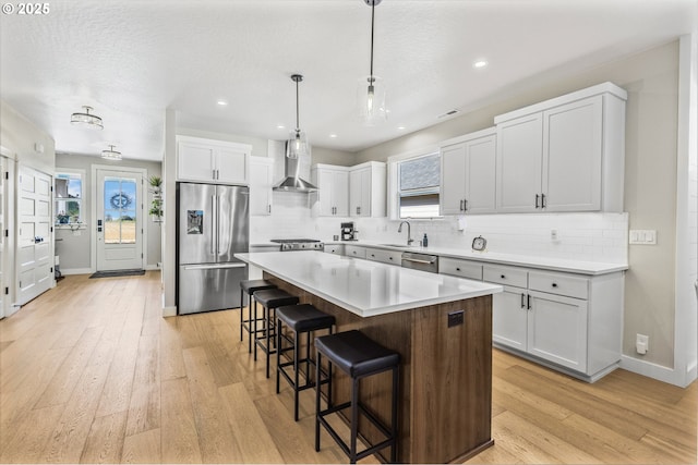 32750 Macy St, Eugene, OR 97408 - kitchen featuring appliances with stainless steel finishes, wall chimney exhaust hood, a kitchen bar, a kitchen island, and decorative backsplash