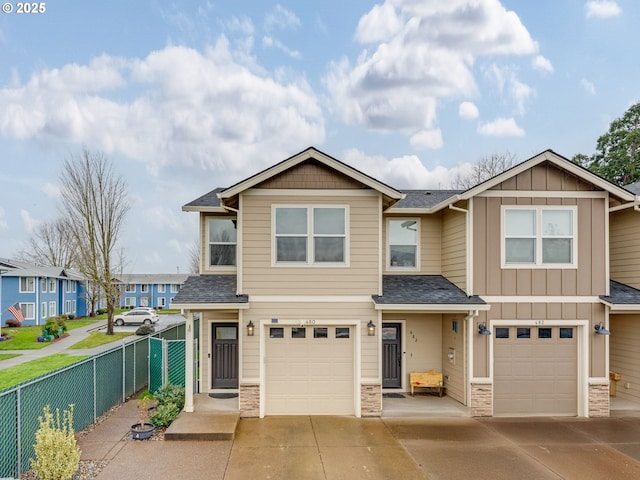 view of front of property featuring stone siding, board and batten siding, an attached garage, and fence