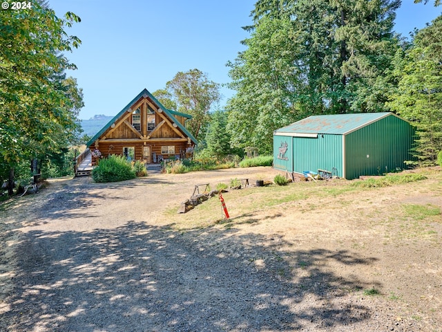 view of front of property featuring an outdoor structure, an outbuilding, driveway, and log siding