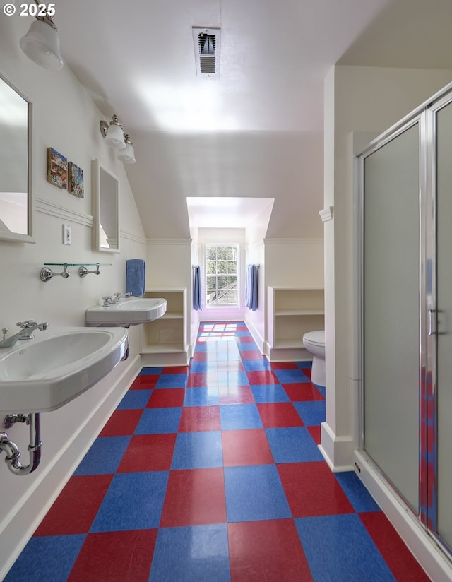 bathroom featuring dual sinks, vaulted ceiling, an enclosed shower, and toilet