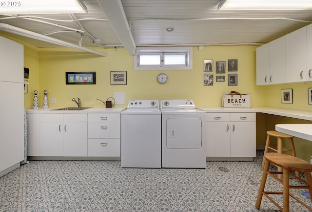 laundry area with washing machine and clothes dryer, sink, and cabinets