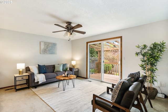 living area with baseboards, visible vents, a ceiling fan, and light colored carpet