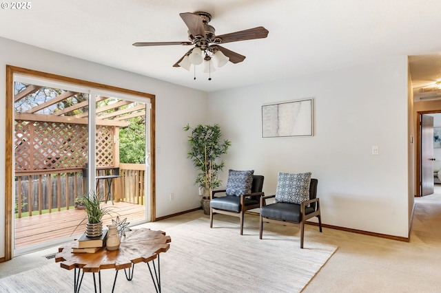 living area featuring a ceiling fan, baseboards, and light colored carpet