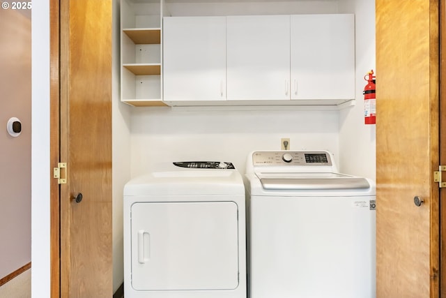 clothes washing area featuring washing machine and clothes dryer and cabinet space