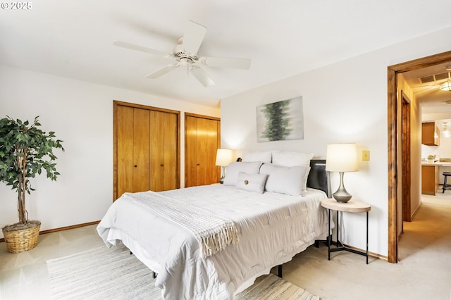 bedroom featuring baseboards, light carpet, and two closets