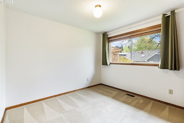 empty room featuring carpet flooring, baseboards, and visible vents