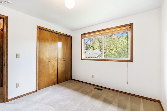 unfurnished bedroom with baseboards, a closet, light colored carpet, and visible vents