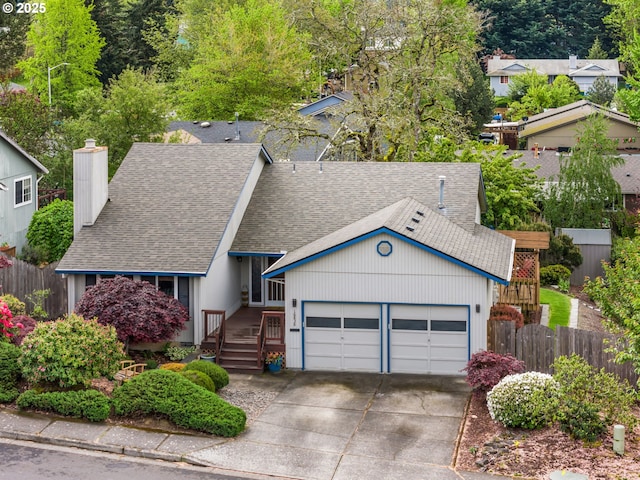 view of front of home with a chimney, roof with shingles, fence, concrete driveway, and an attached garage