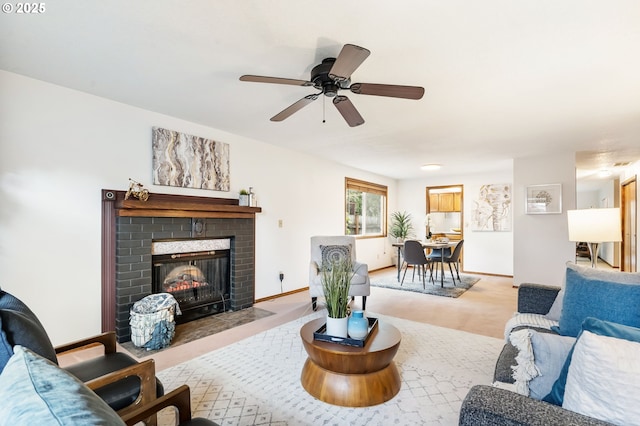 living area with baseboards, a ceiling fan, and a brick fireplace