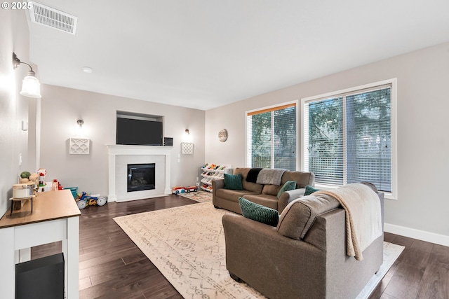 living room with dark wood-type flooring and a tiled fireplace