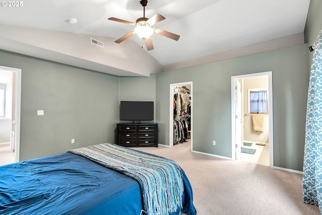 carpeted bedroom featuring a spacious closet, a closet, vaulted ceiling, ceiling fan, and ensuite bathroom