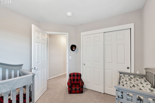 bedroom with a closet, light carpet, and a crib