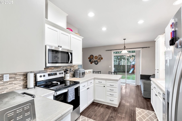 kitchen featuring appliances with stainless steel finishes, white cabinetry, decorative light fixtures, kitchen peninsula, and backsplash