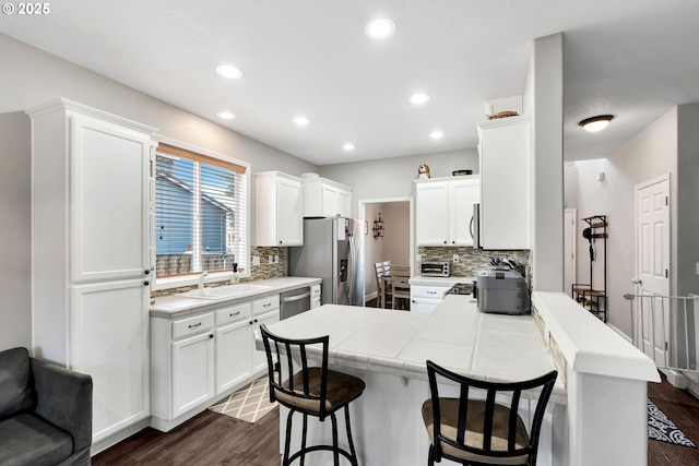 kitchen featuring kitchen peninsula, backsplash, white cabinets, and a breakfast bar area